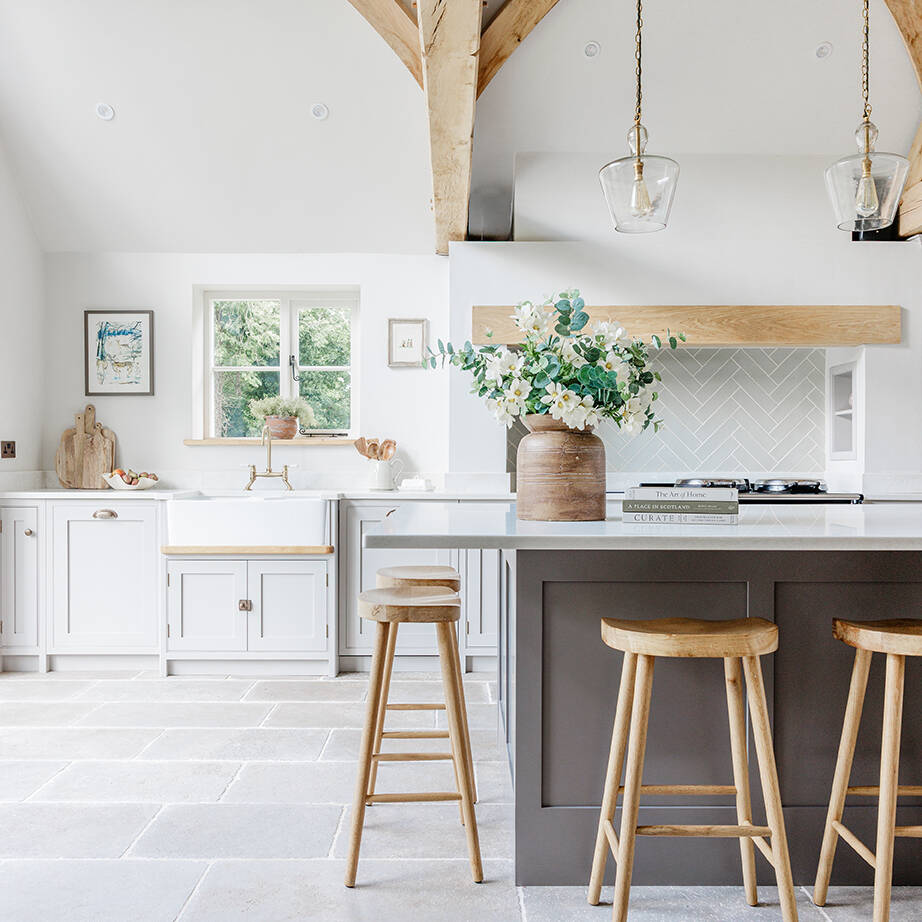 Clermont Gris Aged Tumbled Limestone Floor Tiles in an open kitchen with a grey island and wooden stools