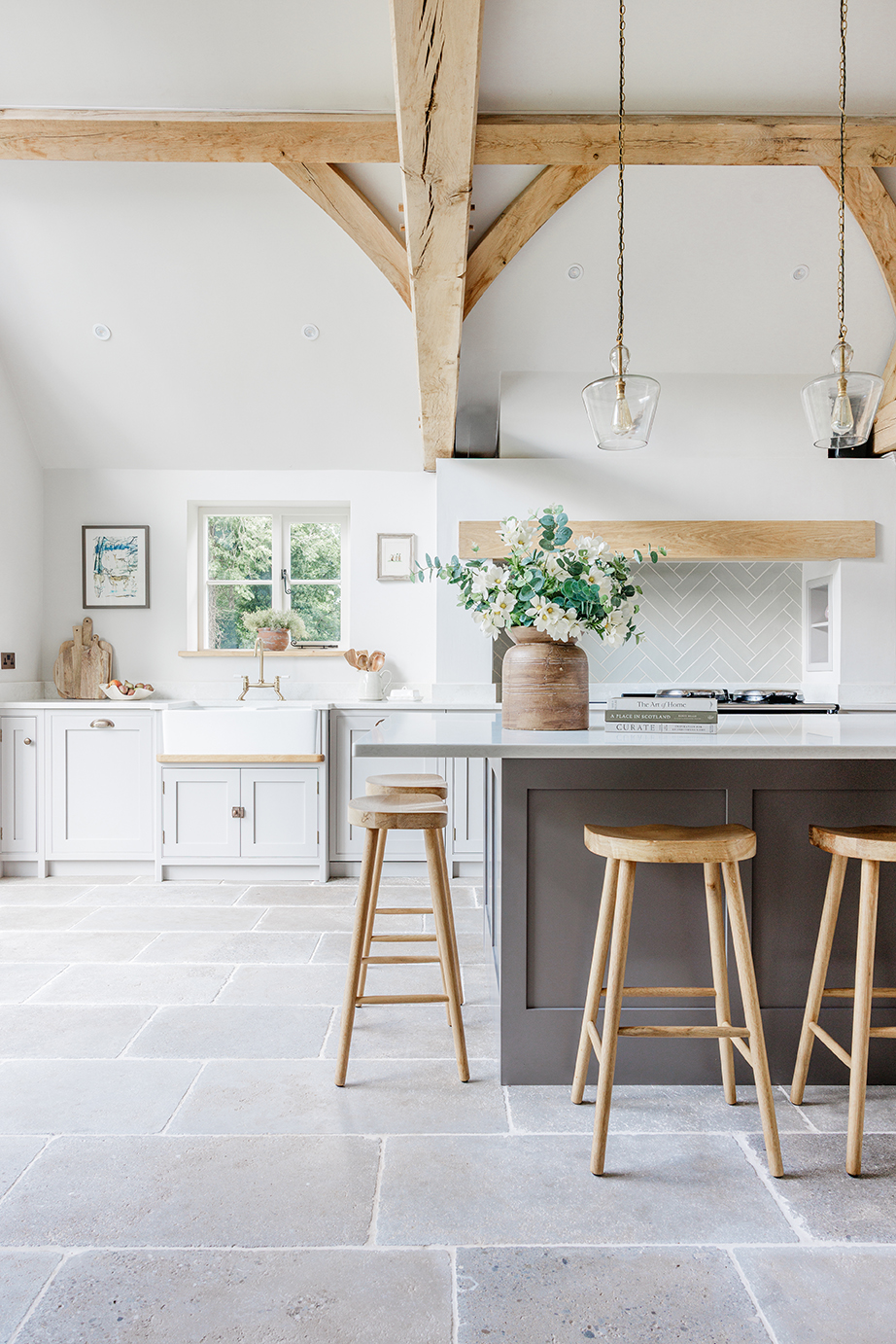Clermont Gris Aged Tumbled Limestone Floor Tiles in an open kitchen with a grey island and wooden stools