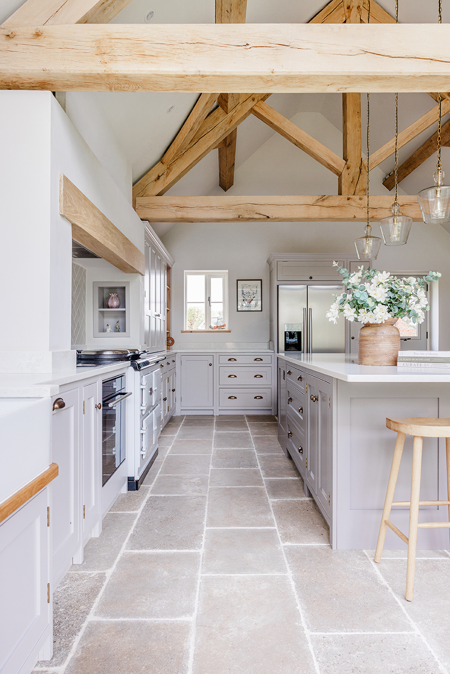 Clermont Gris Aged Tumbled Limestone floor with grey vanity units and a wooden stool with a flower vase on top