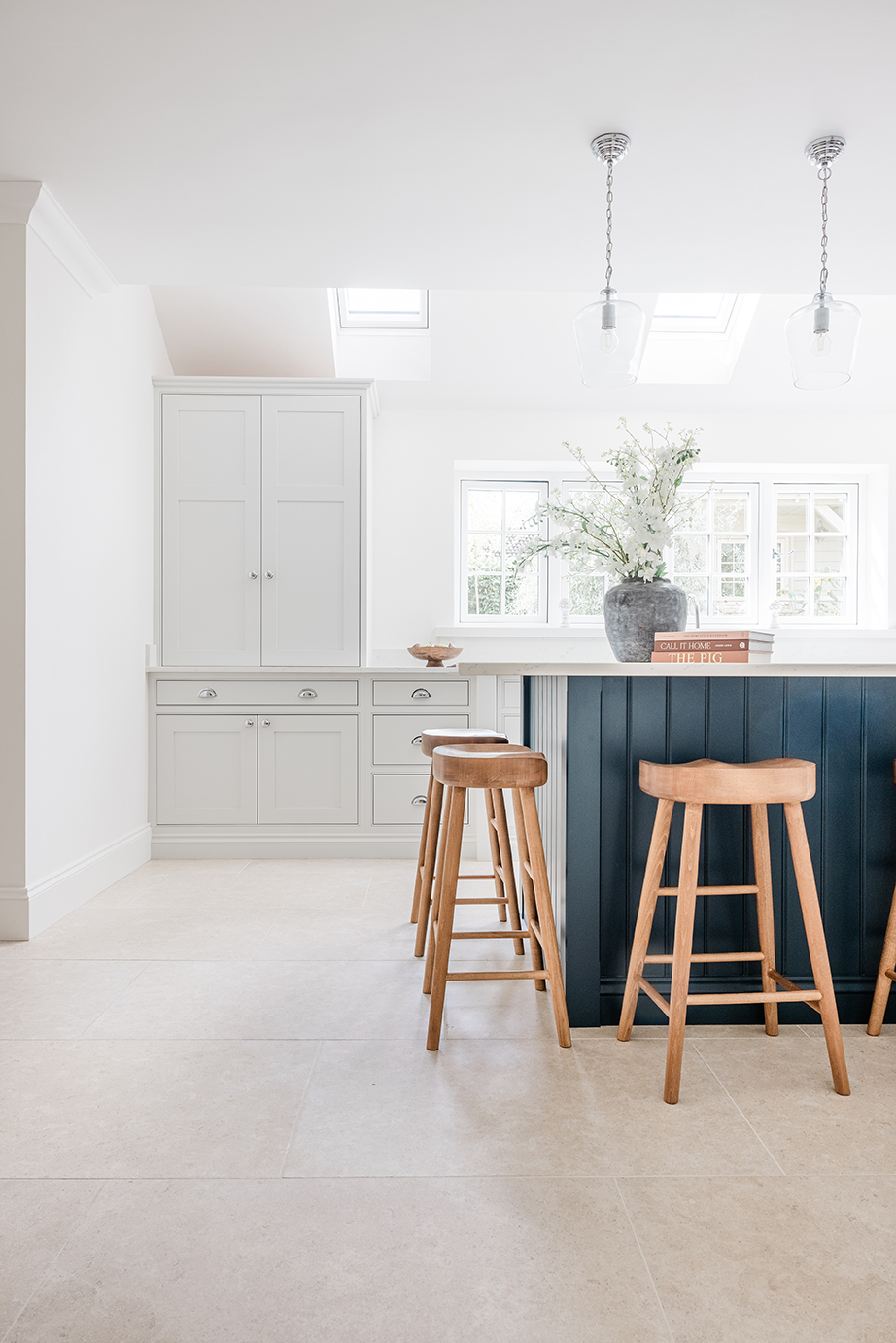 Dijon Rendition Stone Effect Porcelain Flooring with a navy blue island and wooden stools