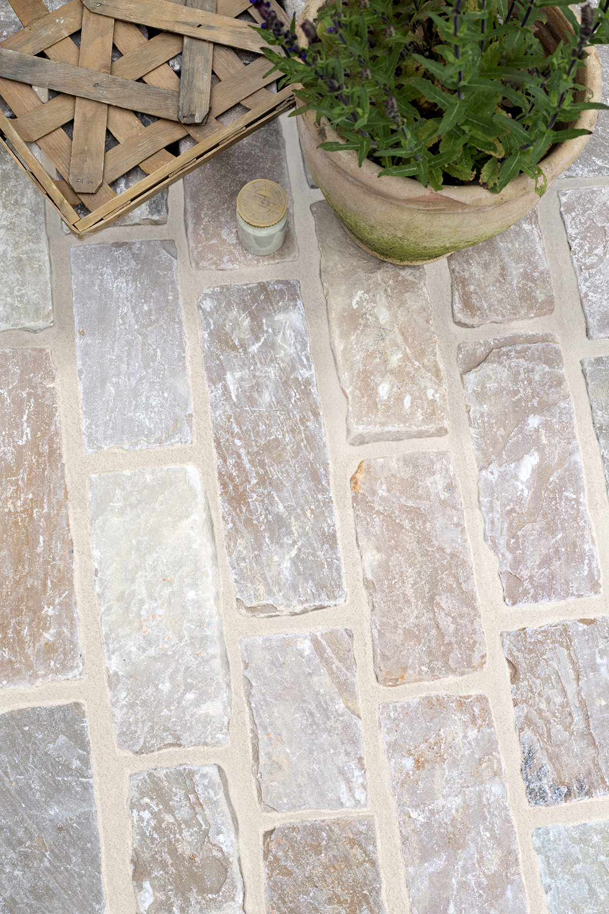 Hempstead Tumbled Sandstone Cobble Stone closeup with garden decor